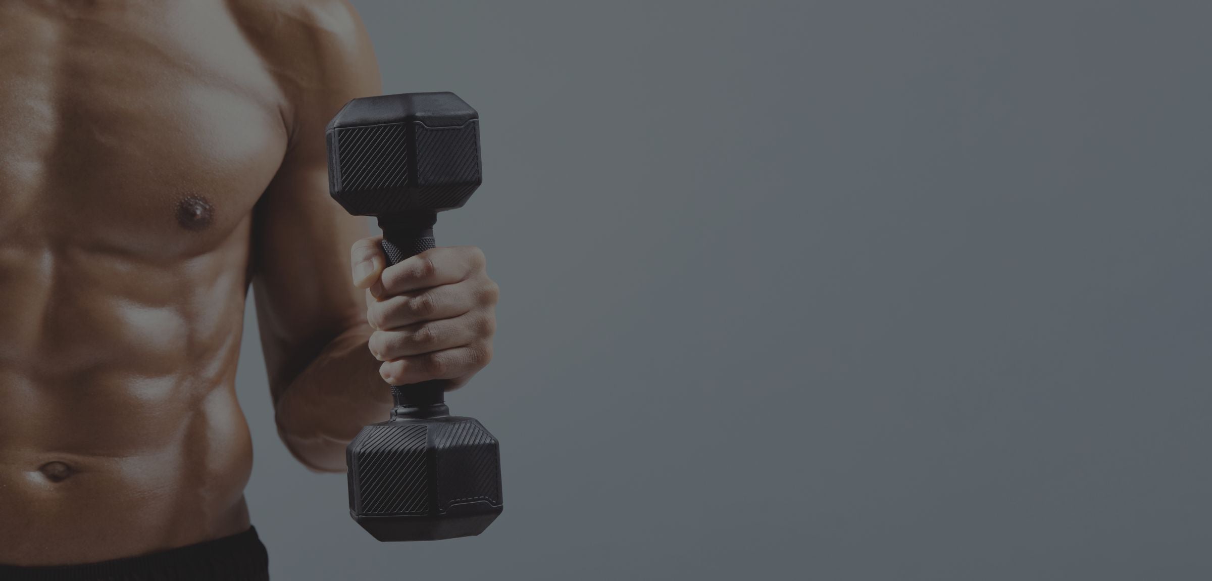 A close-up of a muscular man's torso holding a black hexagonal dumbbell against a solid dark gray background.